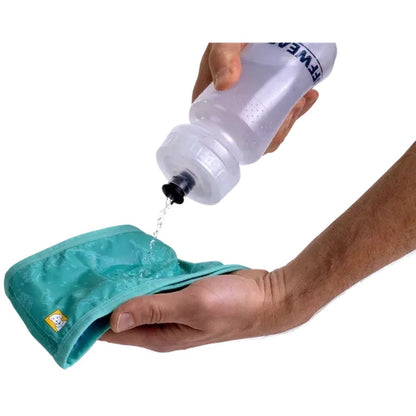 A hand pours water from a bottle onto the AuroraTealPurpl Ruffwear Swamp Cooler Neck Gaiter held in another hand against a white background.