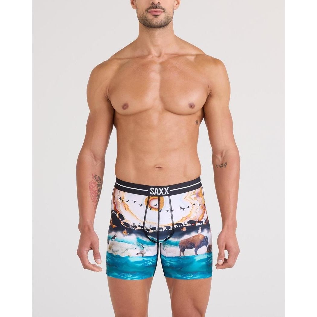 A front view of a shirtless man wearing SAXX GreatMigrationM boxer briefs against a plain white background.