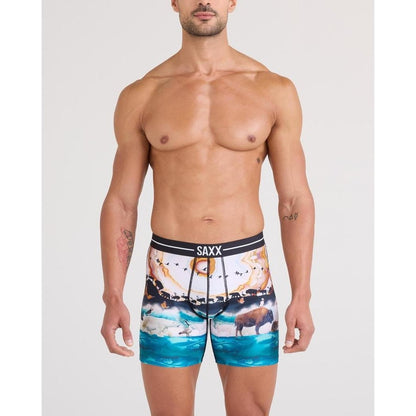 A front view of a shirtless man wearing SAXX GreatMigrationM boxer briefs against a plain white background.