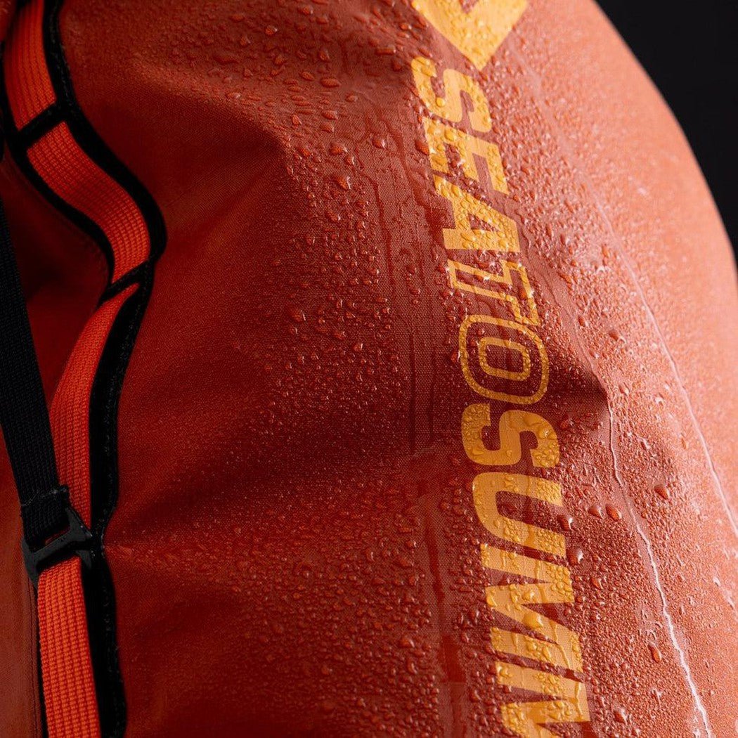 A close-up of the Sea To Summit Big River Dry Pack in Jet Black showing water droplets on the fabric and a black background.
