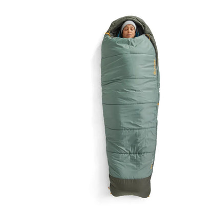 A person wearing a gray beanie is inside the Sea To Summit Boab Synthetic Sleeping Bag 30F|-1C, which is Laurel Wreath Green with a dark gray bottom, shown from a top-down angle against a white