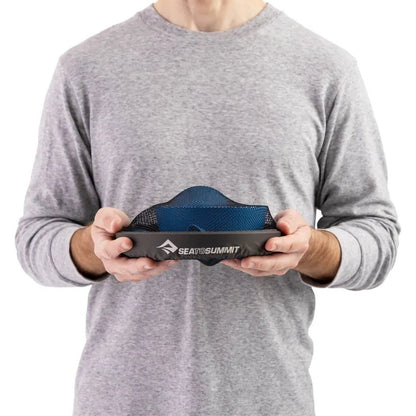 A person in a gray shirt holds the Sea To Summit Camp Dinnerware Set w/ Mesh Sack in Burnt Orange against a white background.