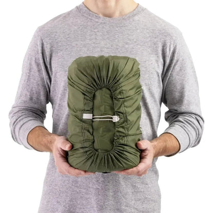 A person in a gray shirt holds the Sea To Summit Camp Plus Self Inflating Mat, showing its green color and central strap against a white background.