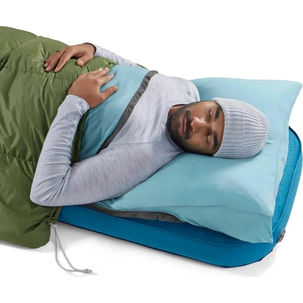 A man sleeps in a Sea To Summit Comfort Blend Sleeping Bag Liner - Rectangular on a blue camping pad with a light blue pillow.