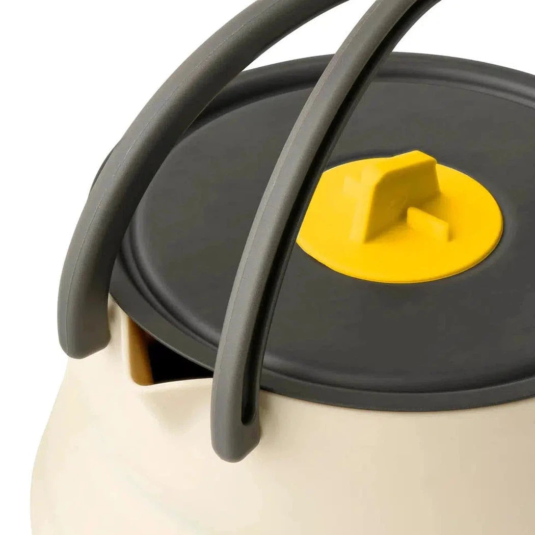 A close-up of the Sea To Summit Frontier UL Collapsible Kettle - 1.1L with its charcoal lid and yellow handle, showing the kettle's beige body and gray carrying handles.