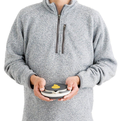 A person wearing a gray fleece holds the Sea To Summit Frontier UL Collapsible Kettle - 1.1L in front of a white background.