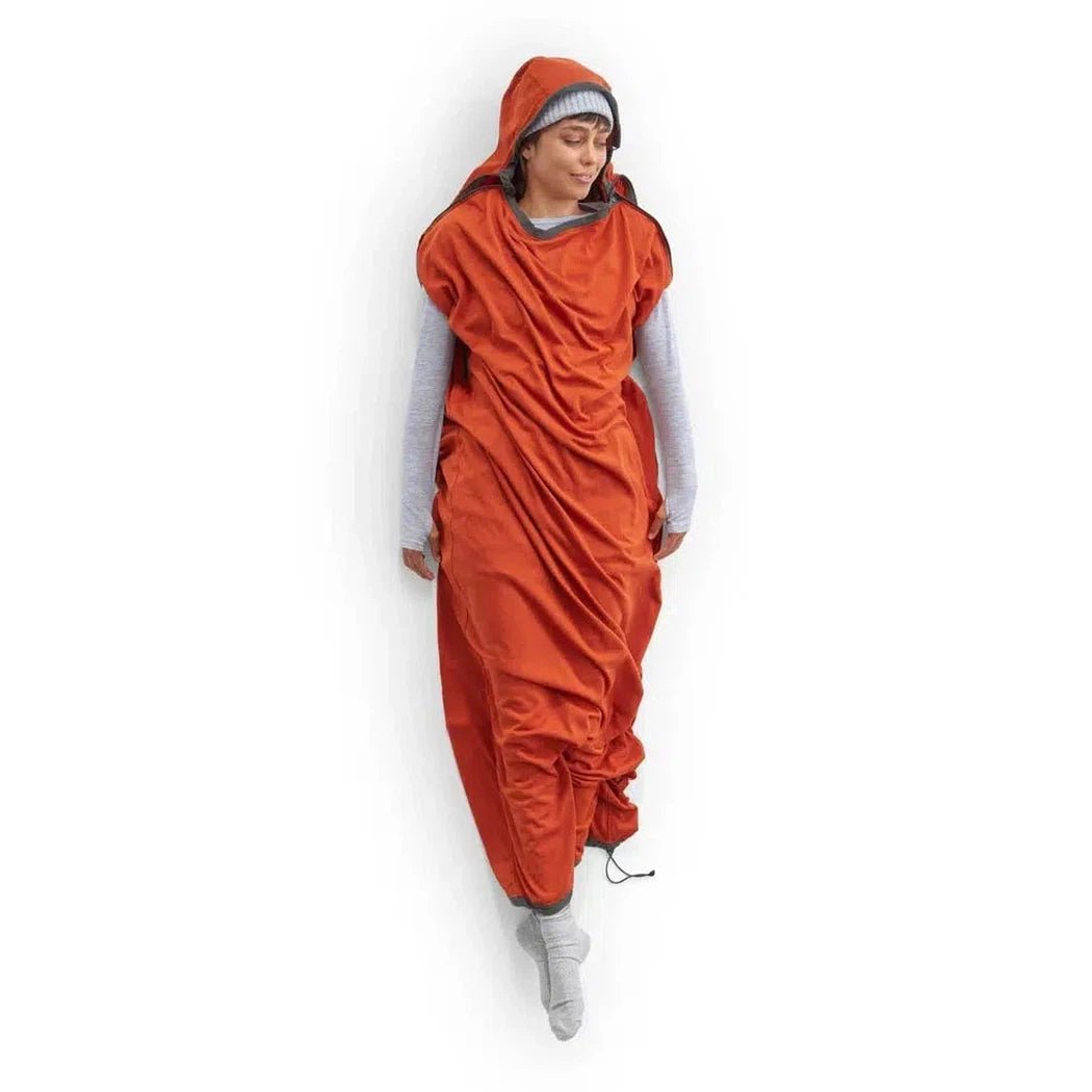 A woman wearing the Sea To Summit Reactor Fleece Sleeping Bag Liner in Mummy w/Drawcord stands against a white background.