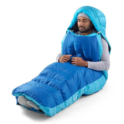 A man wearing a gray long-sleeve shirt and a beanie sits in a Snorkel Blue Sea To Summit Trek Down Sleeping Bag Unisex 30F | -1C against a white background.