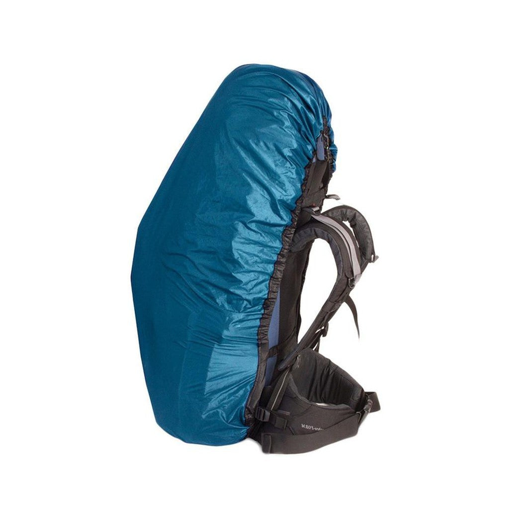 Side view of the Sea To Summit Ultra-Sil Pack Cover in Blue showing the backpack straps and a white background.