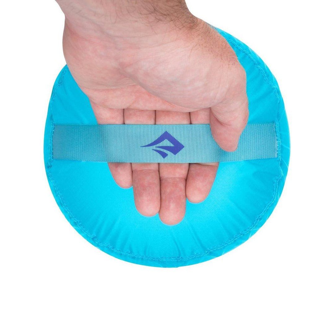 A hand holds the Sea To Summit Ultra-Sil Stuff Sack in Atoll Blue against a white background.