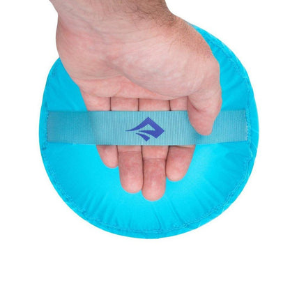 A hand holds the Sea To Summit Ultra-Sil Stuff Sack in Atoll Blue against a white background.