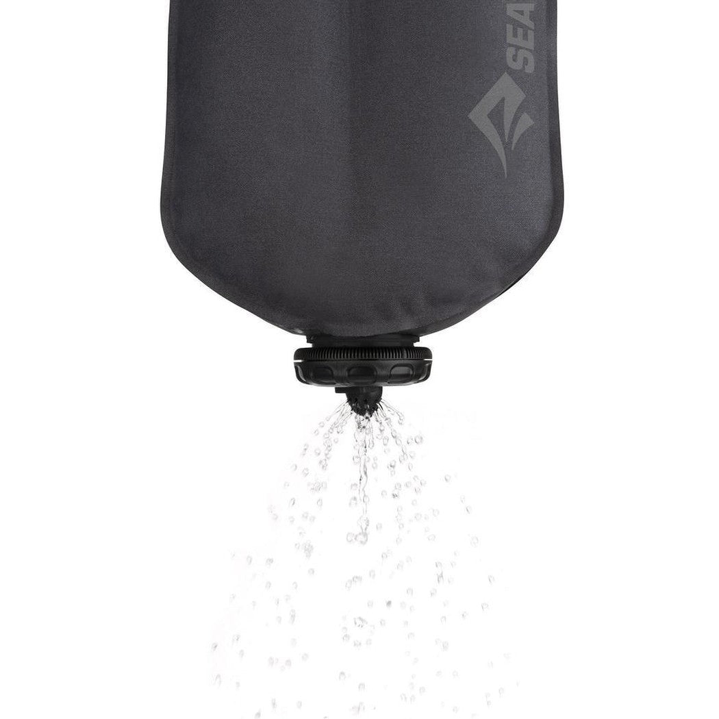 A charcoal Sea To Summit Watercell X hydration bladder pouring water against a white background.