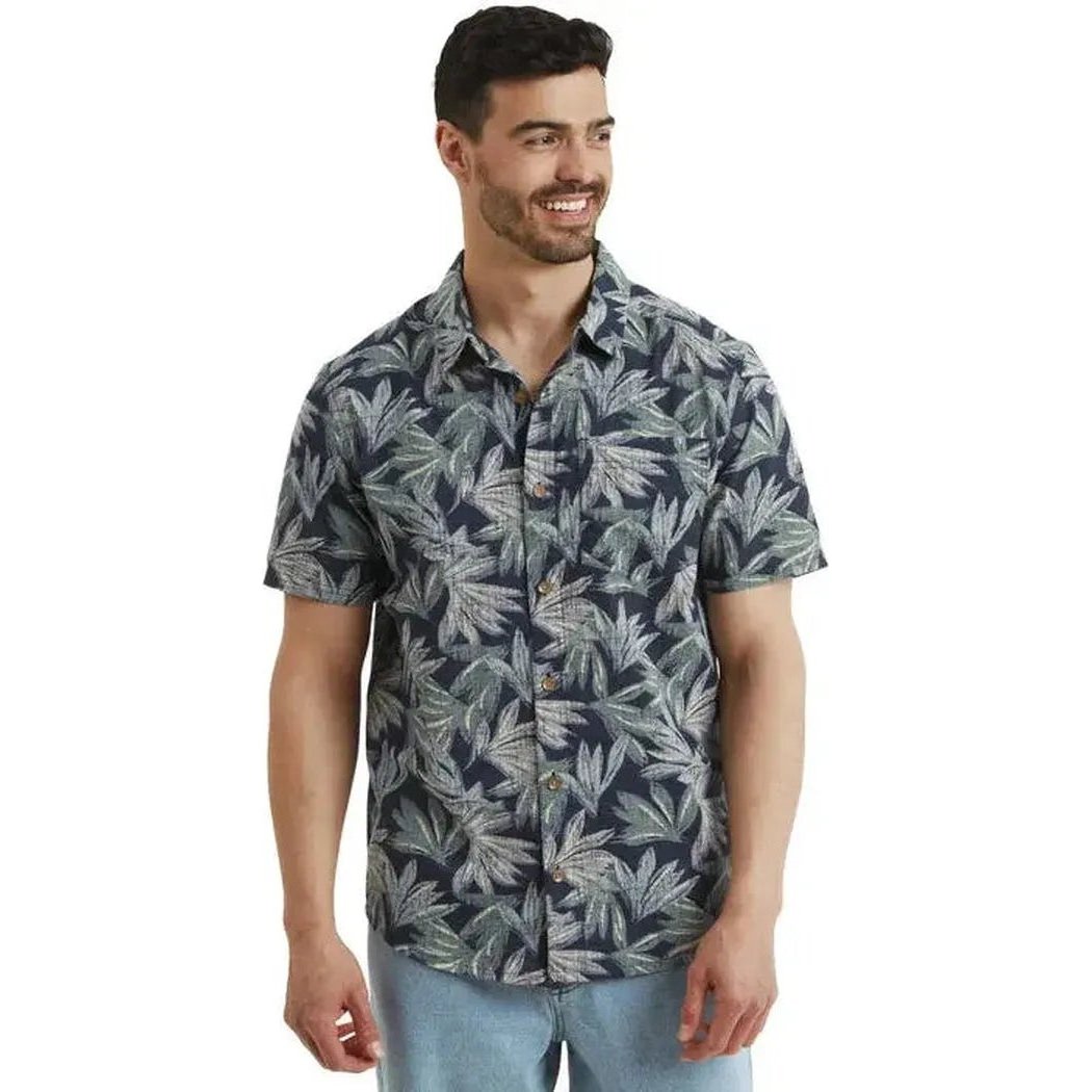 A front view of the Sherpa Adventure Gear Men's Havai Short Sleeve Shirt in Rathee Blue on a model against a white background.