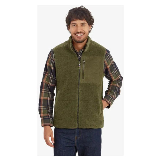 A front view of the Sherpa Adventure Gear Men's Rangeil Vest in Evergreen on a model wearing a plaid shirt and jeans against a white background.