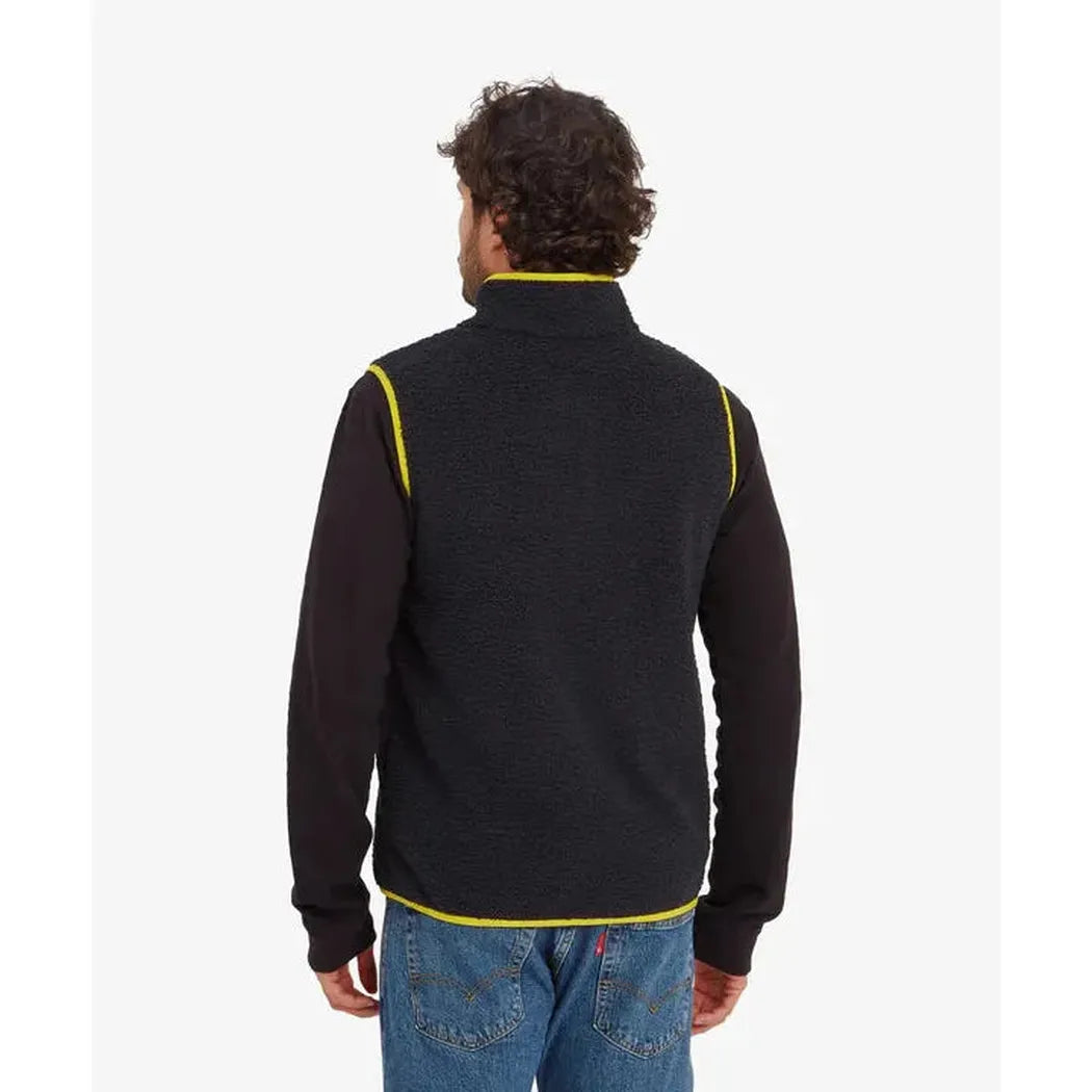 Back view of the Sherpa Adventure Gear Samples - Men's Tarcho Vest in Black on a model wearing blue jeans against a white background.