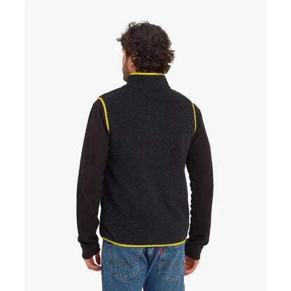 Back view of the Sherpa Adventure Gear Samples - Men's Tarcho Vest in Black on a model wearing blue jeans against a white background.