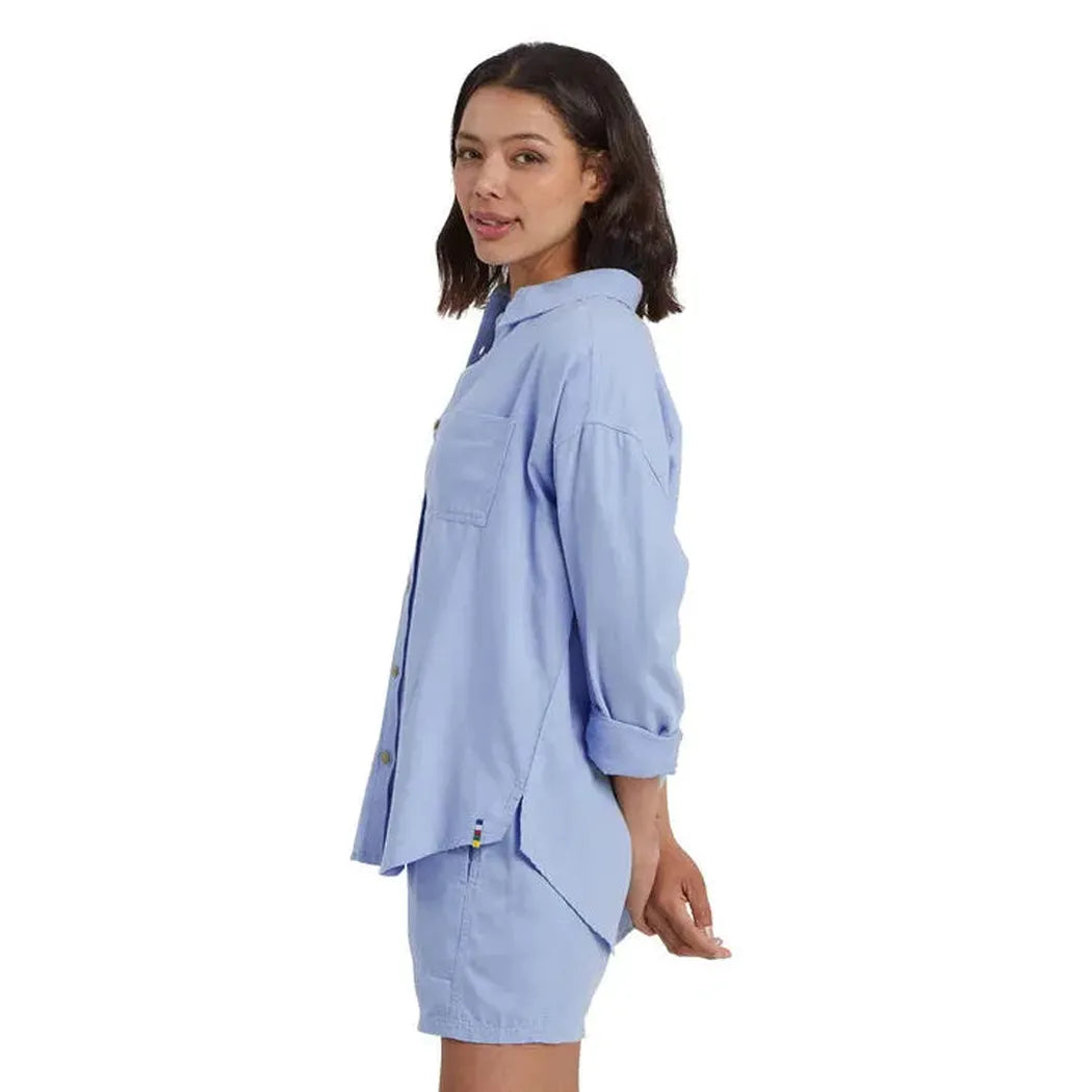 Side view of the Sherpa Adventure Gear Women's Palmo Long Sleeve Shirt in Sky showing the rolled cuffs and a model wearing it against a white background.