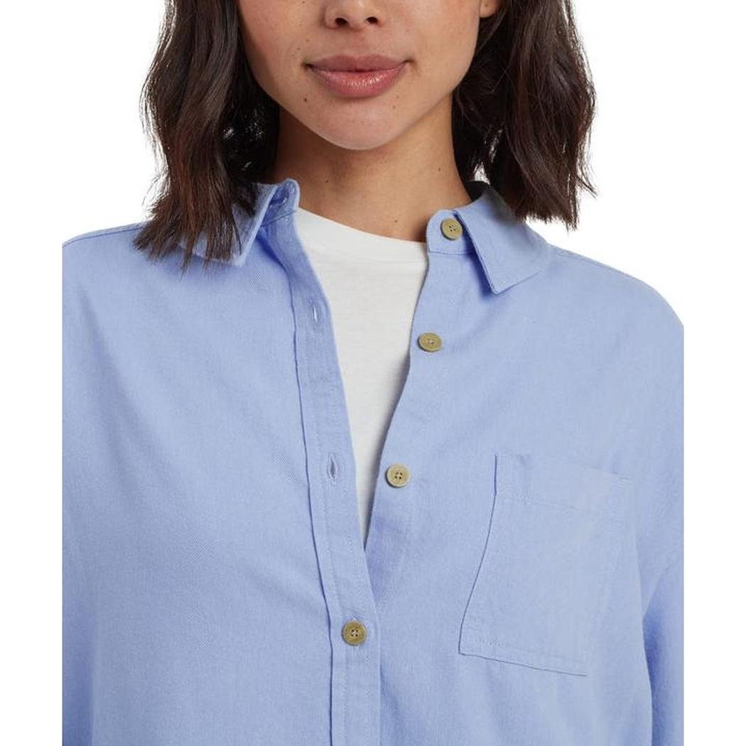 A front view of the Sherpa Adventure Gear Women's Palmo Long Sleeve Shirt in Sky with a white undershirt and a plain white background.