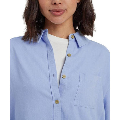 A front view of the Sherpa Adventure Gear Women's Palmo Long Sleeve Shirt in Sky with a white undershirt and a plain white background.