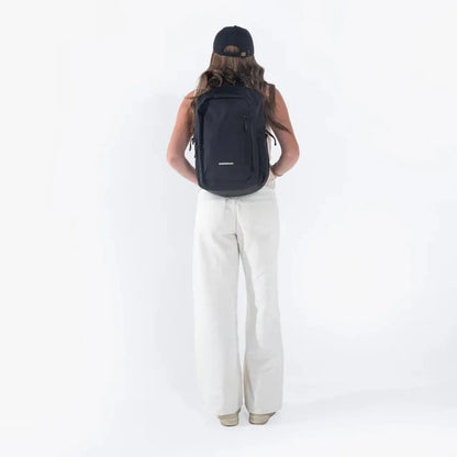 Back view of the Sherpani Getway backpack in Con Leche on a model wearing white pants against a white background.