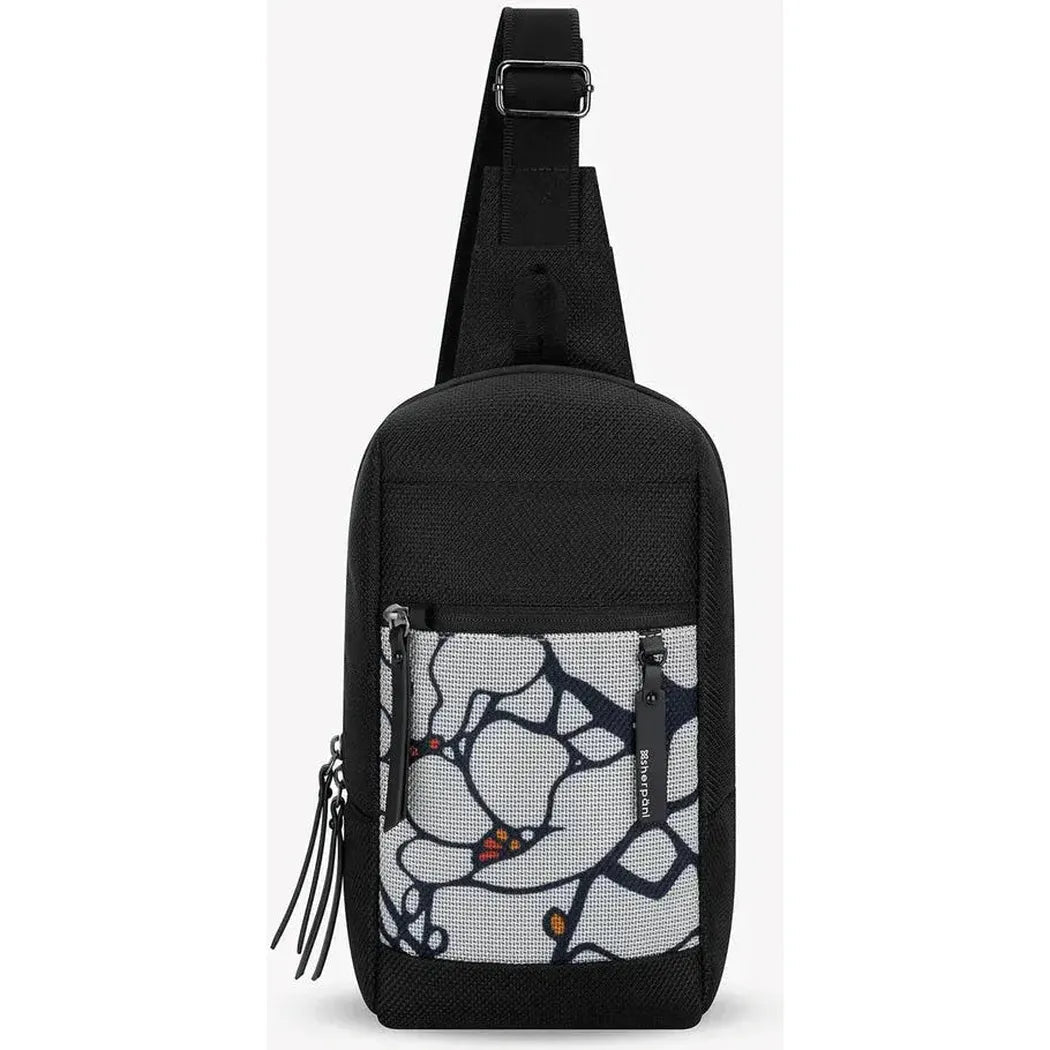 The Sherpani Metro AT crossbody bag in Aloe Mist features a front pocket with a floral print and adjustable strap, photographed against a plain white background.