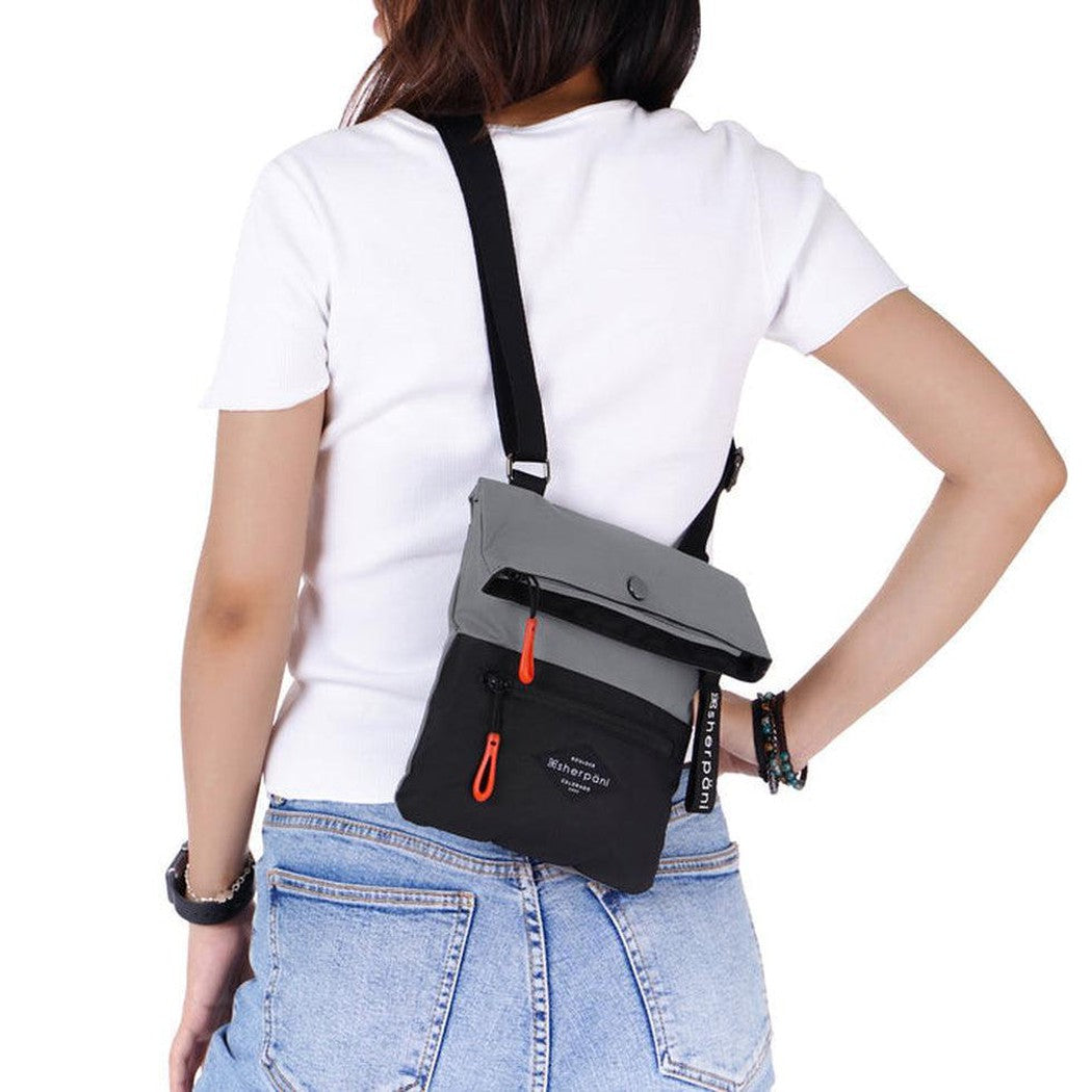 Back view of the Sherpani Pica Raven bag on a model wearing a white tee and blue jeans against a white background.
