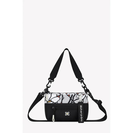 A front view of the Sherpani Skye bag in Alchemy with a black strap and white floral pattern against a plain white background.
