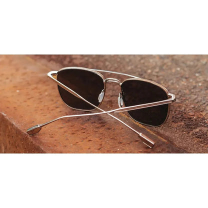 Gold and walnut Shwood Ashland sunglasses with dark lenses resting on a rusted surface.