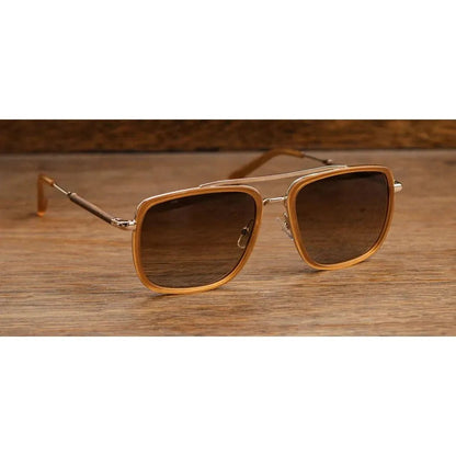 A front view of the Shwood Grant sunglasses with caramel and gold frames on a wooden surface.