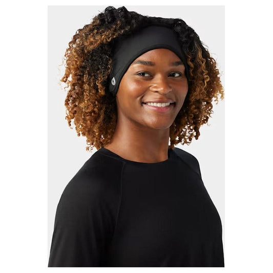 A front view of the Smartwool Active Fleece Wind Headband in Black on a model with curly hair against a plain background.
