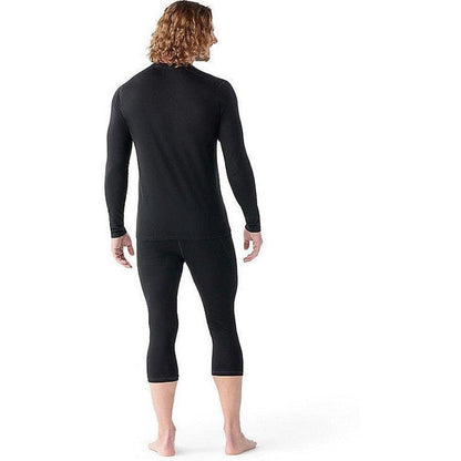 Back view of the Smartwool Men's Classic All-Season Merino Base Layer Long Sleeve in Black on a barefoot model against a white background.