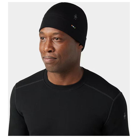 A man wears the black Smartwool Thermal Merino Reversible Cuffed Beanie in a side view against a plain white background.