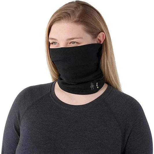 A woman wearing a black Smartwool Thermal Reversible Neck Gaiter against a white background.
