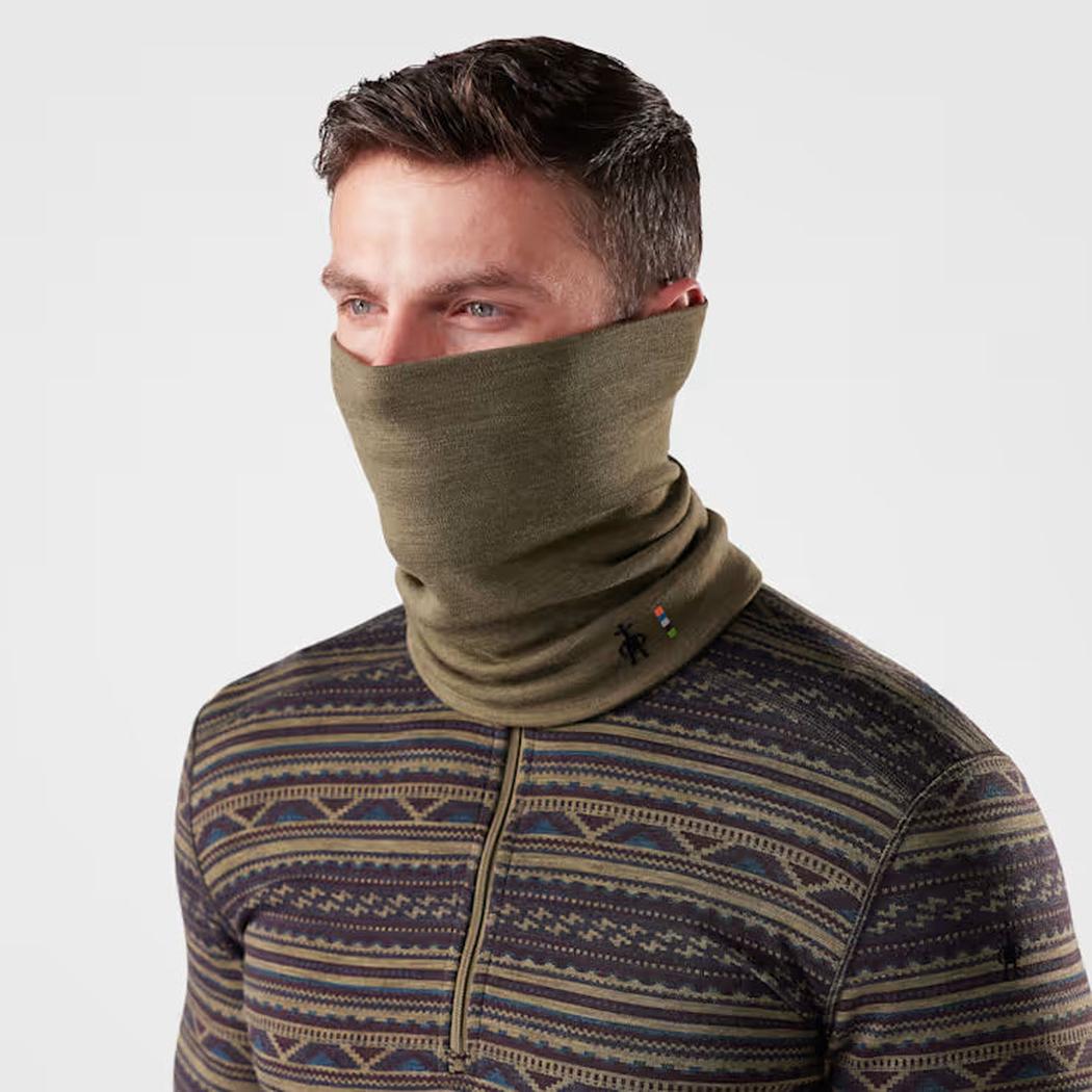 A front view of the Smartwool Thermal Reversible Neck Gaiter in Black/Black on a model wearing a patterned zip-up top against a plain white background.
