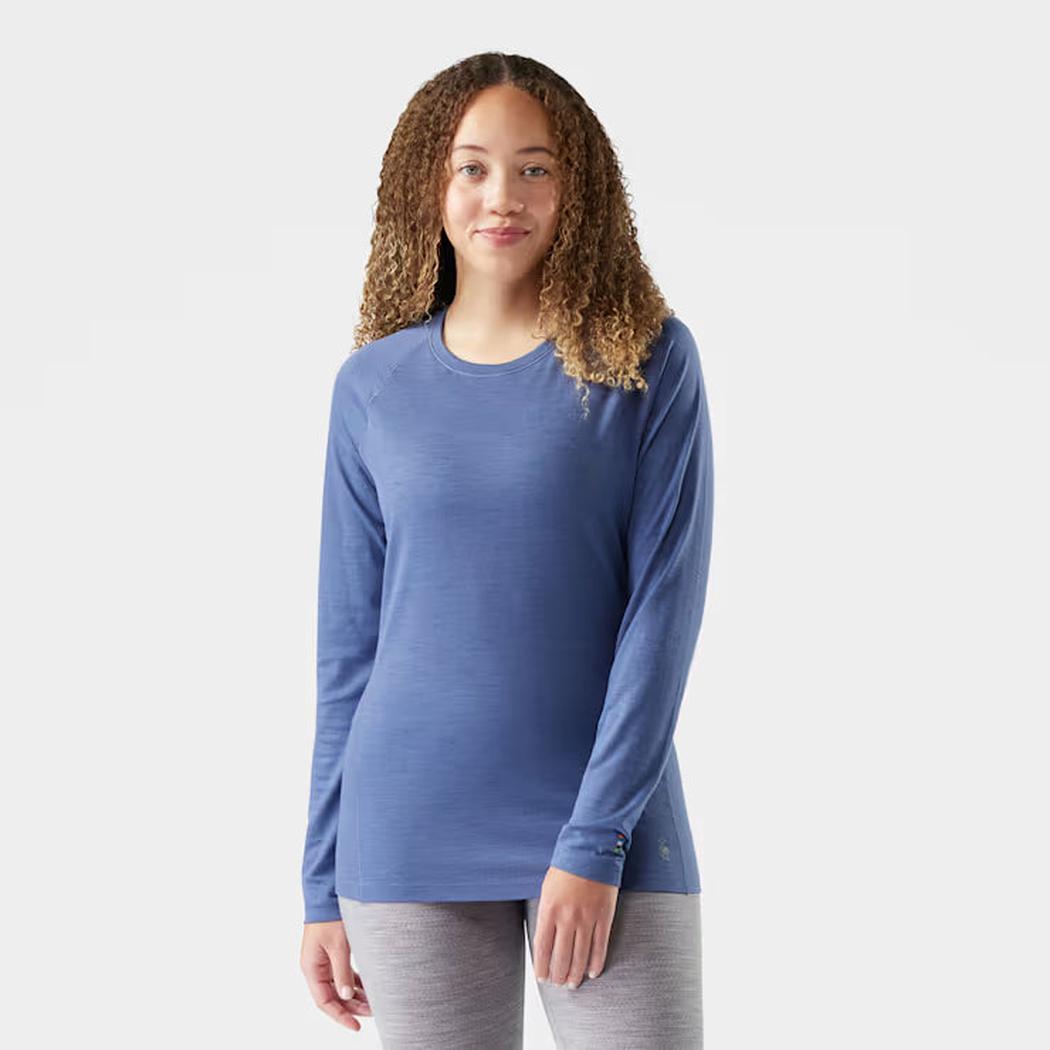 A front view of the Smartwool Women's Classic All-Season Merino Base Layer Crew in Green Tea on a model wearing gray leggings against a plain white background.