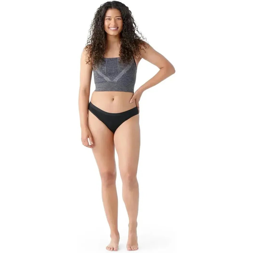A model wearing the Smartwool Women's Merino Bikini Boxed in Black stands against a white background.