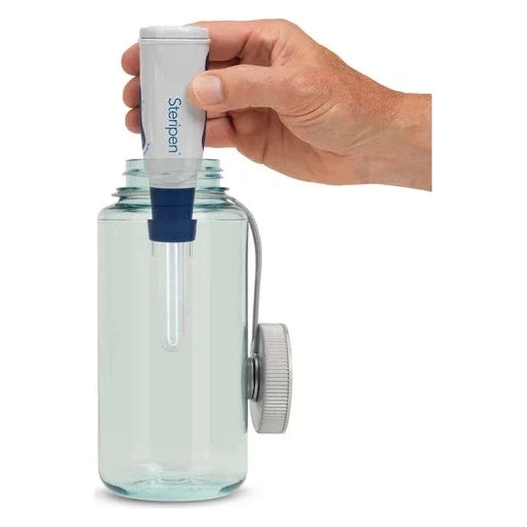 A hand holds the Steripen Classic 3 UV Water Purifier over a clear glass water bottle with a white cap.