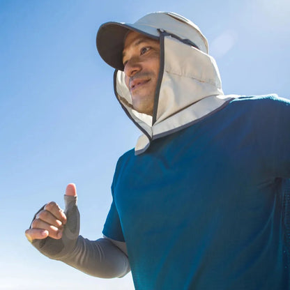 A man wearing the Sandstone Sunday Afternoons Sun Guide Cap runs outdoors under a clear blue sky.