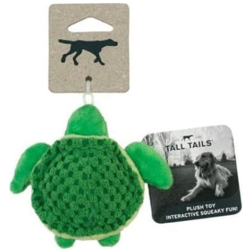 A green Tall Tails baby turtle squeaky toy with a knitted shell and attached hang tag, shown from the back against a white background.