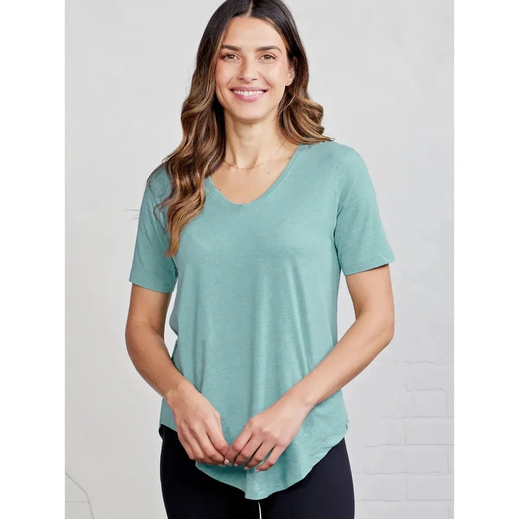 A woman wearing the Tasc Women's Longline Tee in Black Slub stands against a light gray background.