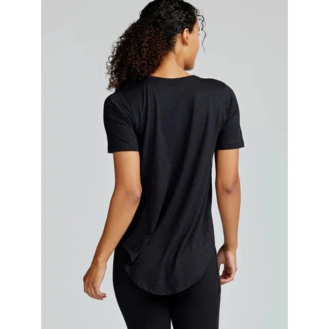 Back view of the Tasc Women's Longline Tee in Black Slub on a model against a light gray background.