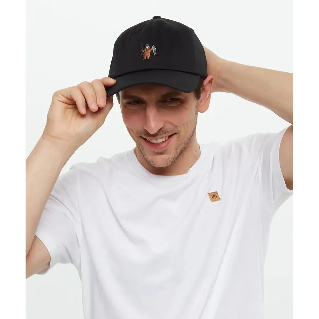 A man wearing the Tentree Sasquatch Peak Hat in Agave Green Hammock adjusts it against a white background.