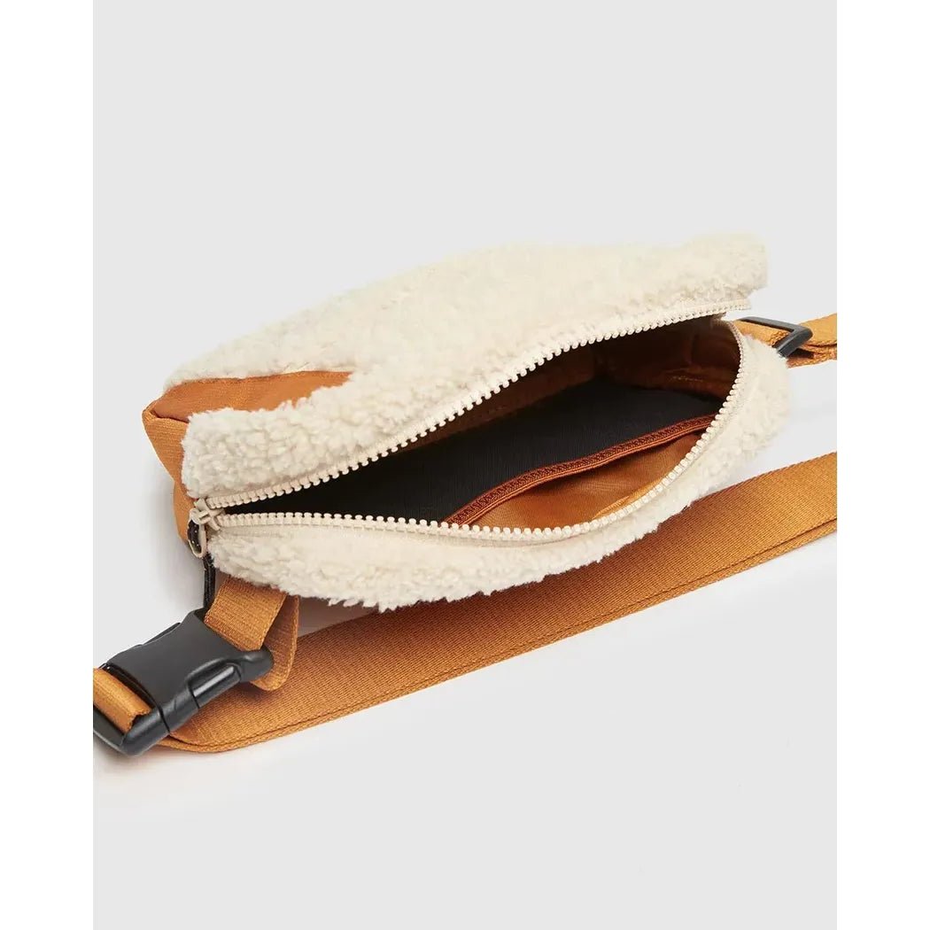 A side view of the Tentree Valdes Hip Pack in BurCarameWarOak showing the zippered opening and tan strap against a white background.