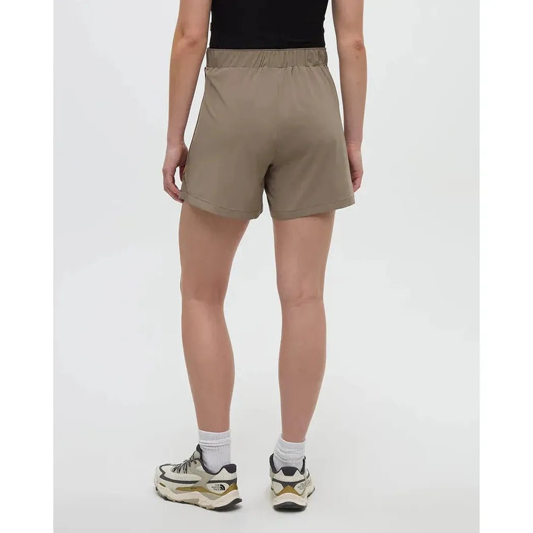 Back view of the Tentree Women's Solstice Short in Clay on a model wearing white socks and sneakers against a white background.