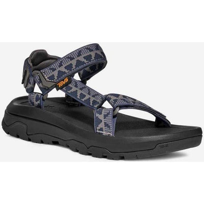 Side view of the Teva Men's Hurricane XLT3 in Criss Cross Navy/ Grey showing the crisscross strap pattern and thick lugged outsole against a white background.