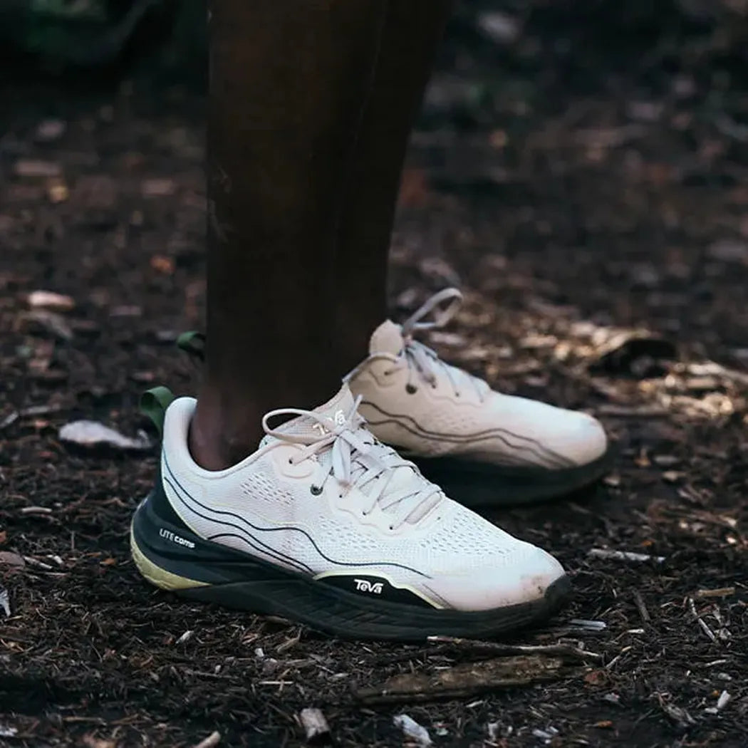 A close-up of a person wearing Teva Men's Trailwinder Low shoes in Unexplored/ Vapor Blue on a forest floor.