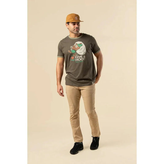 A man wearing The Landmark Project Give a Hoot, Don't Pollute olive/dark oak t - shirt stands against a neutral background.