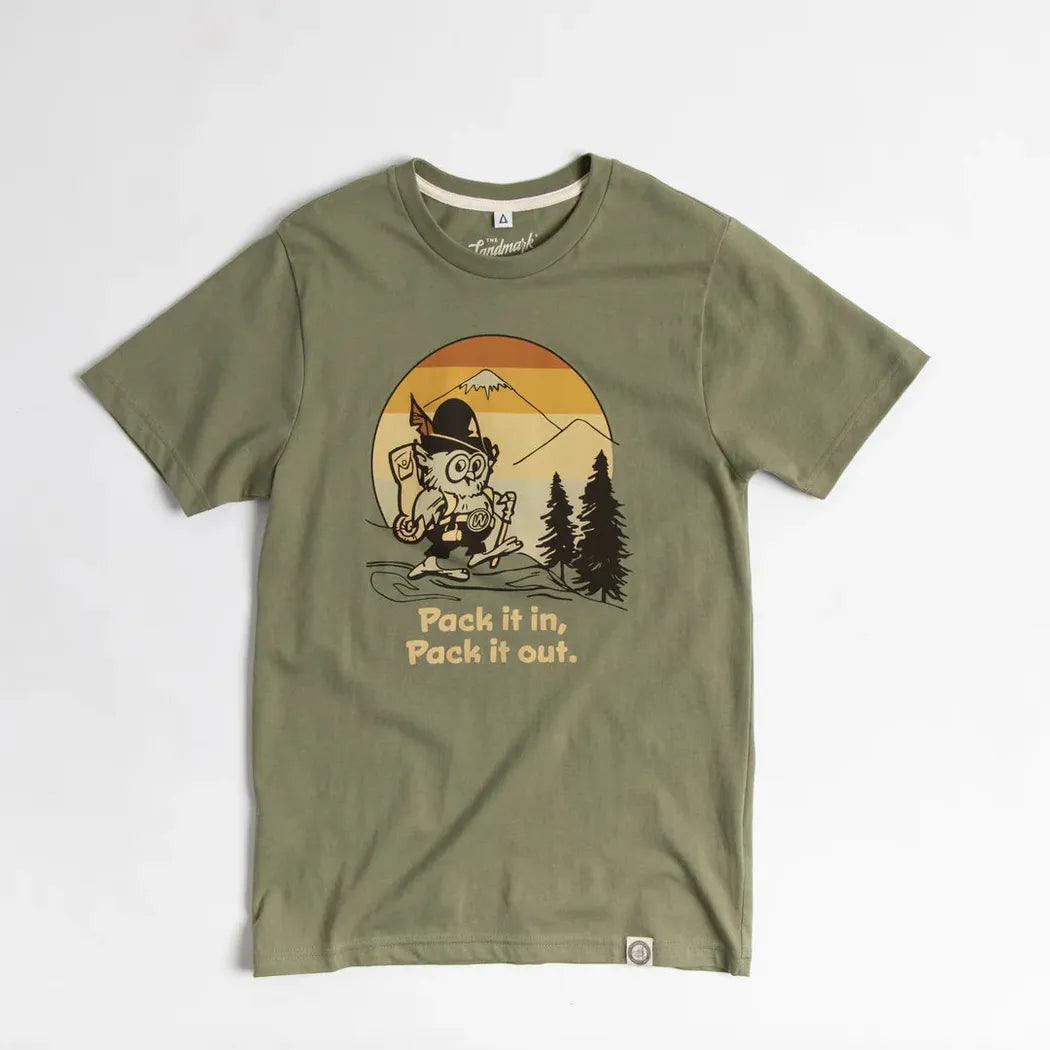 Olive The Landmark Project Pack It in, Pack It Out t - shirt laid flat on a white background with a cartoon character and trees on the front.