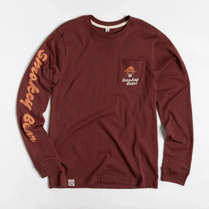 A front view of the Angostura The Landmark Project Spark A Change Unisex Long Sleeve Tee w/ Pocket with a pocket on the chest and text on the sleeve against a white background.