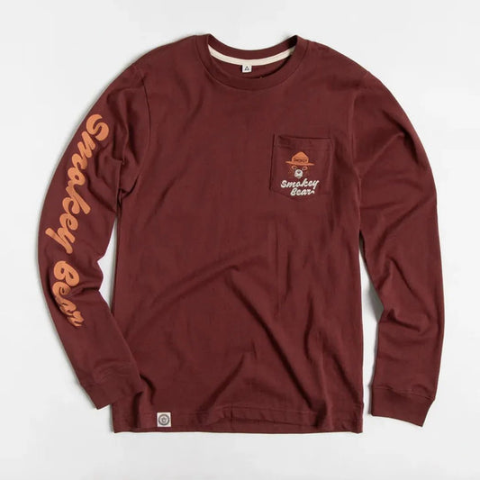 A front view of the Angostura The Landmark Project Spark A Change Unisex Long Sleeve Tee w/ Pocket with a pocket on the chest and text on the sleeve against a white background.
